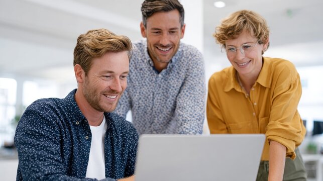 Three people working together at a computer in an office setting.