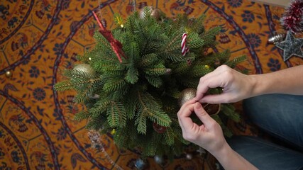 Decorating Christmas tree with ornaments. Scene captures festive spirit of holiday season in cozy living room. Top view.