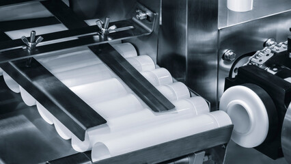 Automatic polyethylene plastic bag production machine with lighting effect. Close-up of the roller of the plastic bag production machine in the light blue scene. product packaging concept.