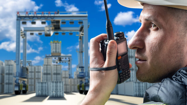 Port cargo coordination specialist communicates by radio while overseeing container lifting operations, ensuring safe workflow and precise handling at the loading terminal.