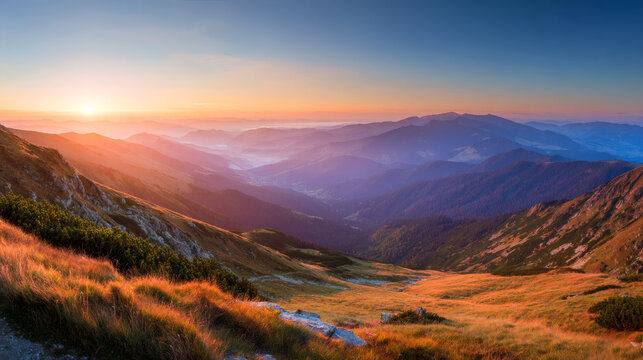 Breathtaking sunrise over a vast mountain range with rolling hills and golden grass