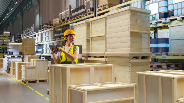 Warehouse operations specialist verifies crate labeling and stock positions using a digital tablet while coordinating inventory flow in a busy storage facility. - Powered by Adobe