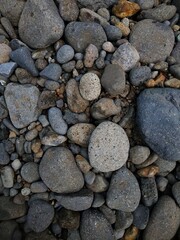 A close-up view of smooth river stones in various sizes and natural earthy tones, creating a textured and organic pattern.
