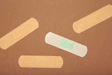 Medical sticking plasters on brown background. First aid item