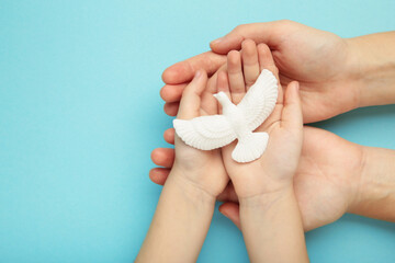 Hands of family with dove on blue background. Mother and child