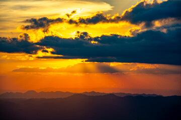 Scenic sunrise above mountain layers and morning fog under a vibrant sky.