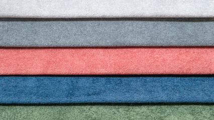 Fototapeta premium A row of different colored towels. The towels are blue, green, pink, and red. They are stacked on top of each other