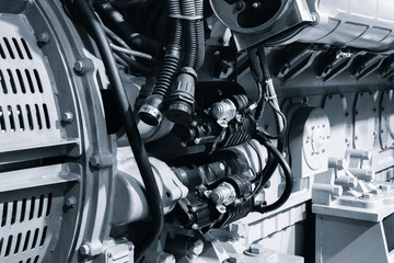 large blue diesel engine generator with  black hose attached to it. hose connected to engine and...