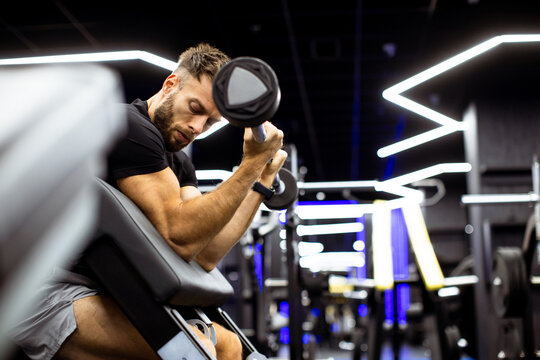 Man performing bicep curls in modern gym with stylish lighting