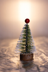 A small decorative Christmas tree with a wooden base, covered in white glitter