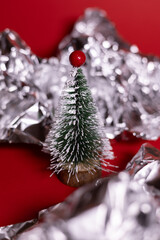 A small decorative Christmas tree with a wooden base, covered in white glitter, standing on a bright red background.
