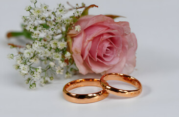 Golden wedding rings with delicate pink rose and baby's breath celebrate love and commitment for a lifetime of happiness