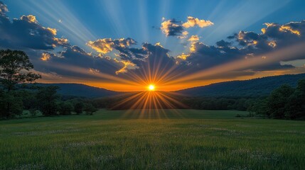 Sunset over a grassy valley with vibrant sun rays