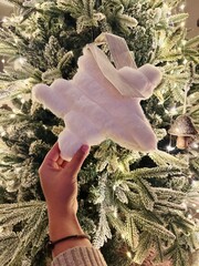 Hand Decorating Christmas Tree with Star Topper and Fireplace Burning Behind – Warm Festive Setting