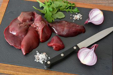 Raw Chicken Livers with Red Onions and Herbs on a Dark Cutting Board high angle