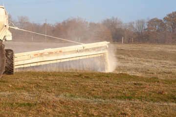 Close up on a chemical drop boom spreader spreading fertiliser on a farm pasture in winter, chemical fertilisation © gozzoli