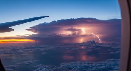 Airplane window view of storm with lightning over cloudscape at sunset