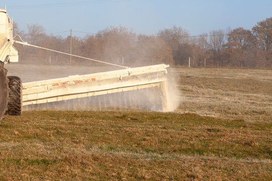 Close up on a chemical drop boom spreader spreading fertiliser on a farm pasture in winter, chemical fertilisation