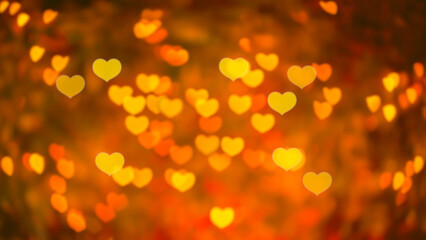 Abstract beautiful blurred gold-yellow orange and red colored of heart bokeh like autumn leaves from ornamental lights flickering in the park. Background for Autumn season, Valentine or Love concept.