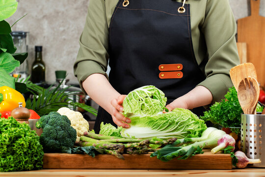 private chef carefully selects and cuts vibrant vegetables and herbs at well-organized kitchen counter, emphasizing healthy cooking