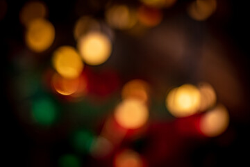 Soft, colorful bokeh lights in red, green, and gold tones creating a festive and dreamy abstract background suitable for holiday and celebration themes.