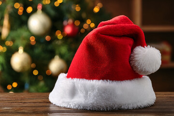 Red Santa Hat on Wooden Table by Christmas Tree