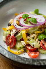 A delightful salad features bright cherry tomatoes, crisp cucumbers, sweet bell peppers, and fragrant basil, perfect for a light lunch in a warm atmosphere
