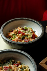 Vibrant salad bursting with red peppers, greens, and crunchy croutons is elegantly presented in a chic bowl. The cozy restaurant atmosphere enhances the dining experience
