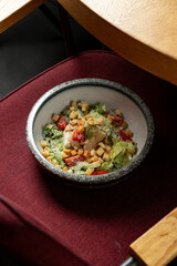 Bright greens and crunchy croutons fill a beautiful bowl, resting on a plush chair in a warm eatery. A delicious option for a midday break with friends