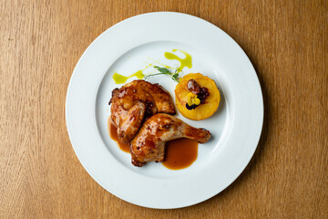 Tender roasted chicken legs glisten with a rich sauce, paired with creamy polenta and garnished artfully. A perfect dish for a warm evening in an inviting atmosphere