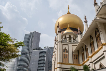 Golden dome of Sultan Mosque with modern skyscrapers in Haji Lane, Singapore showcasing urban contrast