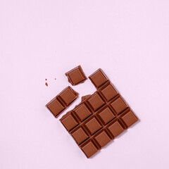 Delicious Milk Chocolate Bar, Broken into Pieces on a Pink Background