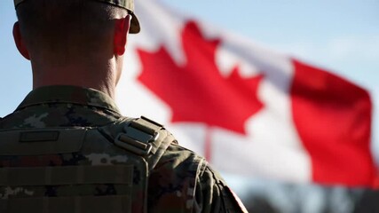 soldier standing in front of canadian flag during outdoor ceremony or event