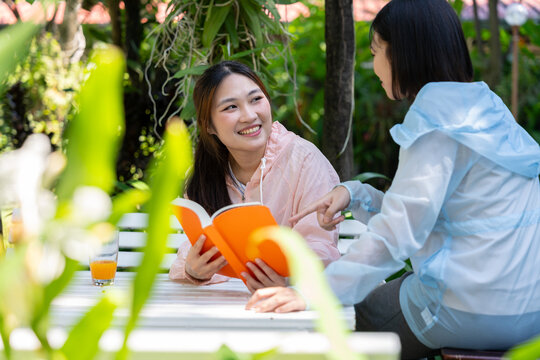 Friendship Blossoms: Two young friends engaged in a heartfelt conversation in a sunlit garden, sharing stories over an open book and building connections.