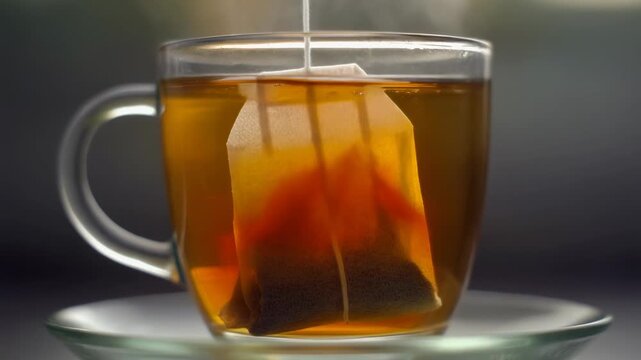 A warm tea moment caught as a sinking teabag releases drifting color through clear hot water