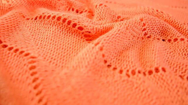 Coral color knitted fabric texture, mercerized. Product from wool. Reverse side. Handwork , Folded in waves and folds textiles, close up fabric. Detailed warm yarn background. Cardigan, sweater