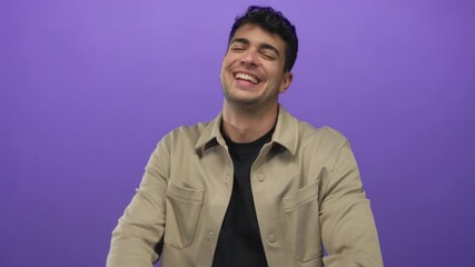 Man lifts finger to point at a background that highlights a hispanic young performer before a purple studio setting to laugh and greet every guy.