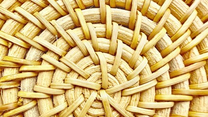 close-up of woven straw basket texture with radial circular pattern in warm yellow tones