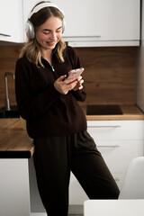 Woman in headphones listening music audio and relax in the kitchen. mobile app for listening to...