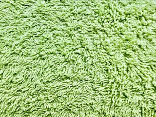 close up of vibrant lime green fluffy terry cloth fabric texture featuring numerous looped fibers and soft wavy surface against subtle light background
