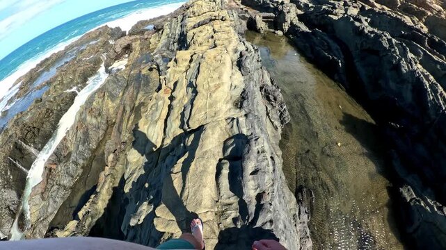 Point of view walking and clambering across rocky crevices and pools of ocean water in Fuerteventura, Spain 