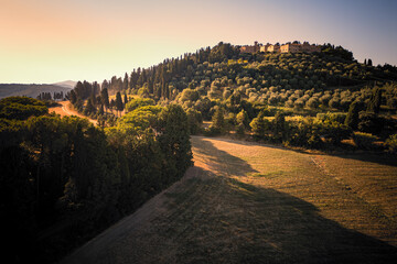 Scenic aerial view of a large old estate on a hill overlooking its olive groves and vineyards in the beautiful late summer Tuscan countryside, Italy