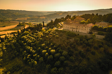 Scenic aerial view of a large old estate on a hill overlooking its olive groves and vineyards in the beautiful late summer Tuscan countryside, Italy