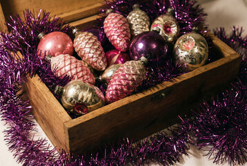 Old New Year's toys from the USSR times in the form of cones, snowflakes. Christmas pink, crimson and red toys on the Christmas tree and silver tinsel in a wooden box