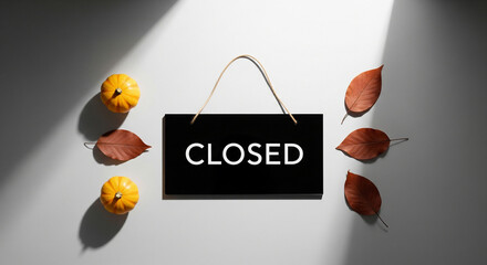 Autumn sign announcing closure, surrounded by seasonal leaves and pumpkins, evoking a sense of the changing season.