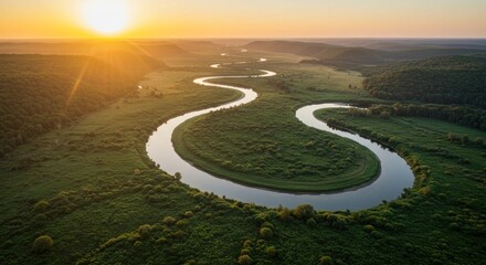 Fototapeta premium Aerial view of a winding river through lush green landscape at sunrise