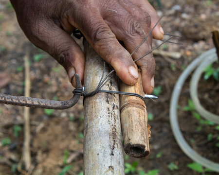 Close-up of a Worker Tying Wire Around Bamboo Poles to Create Structural Support