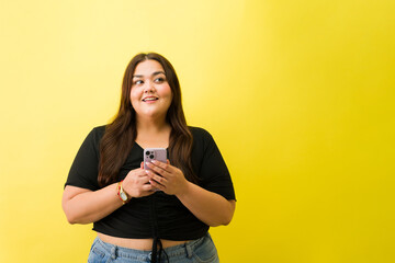 Plus size young woman using smartphone looking away