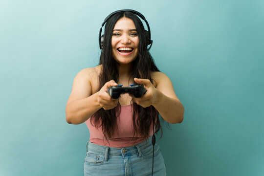 Excited young woman playing video game with controller - Powered by Adobe