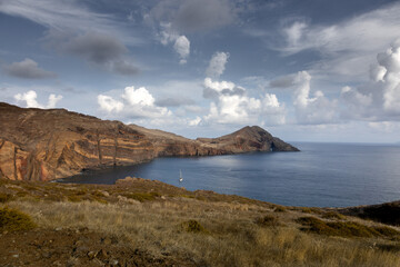Dramatic volcanic cliffs and serene ocean view at Ponta de S&atilde;o Louren&ccedil;o, Madeira Island, Portugal &ndash; panoramic coastal landscape with sailboats, hiking trails, and wild natural beauty.